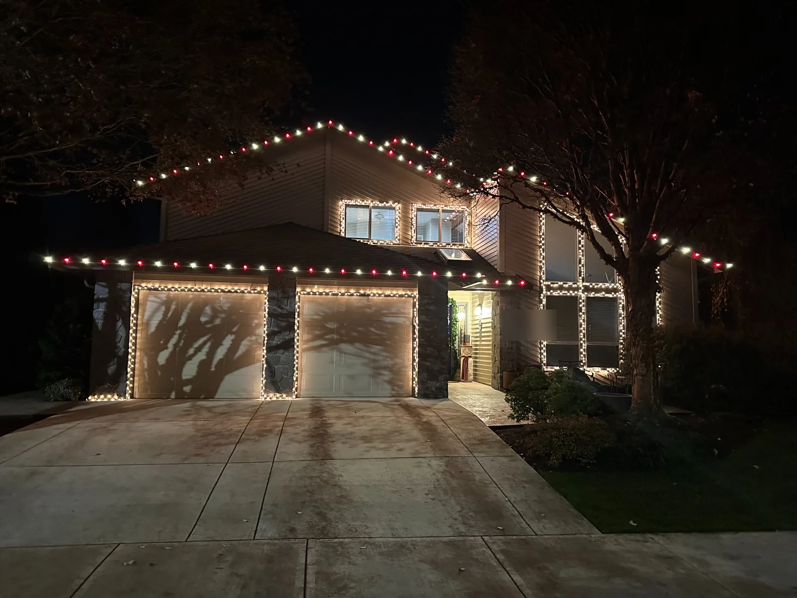 Alternating red and warm white C9 bulbs along the rooflines with outlined windows and garage doors at night