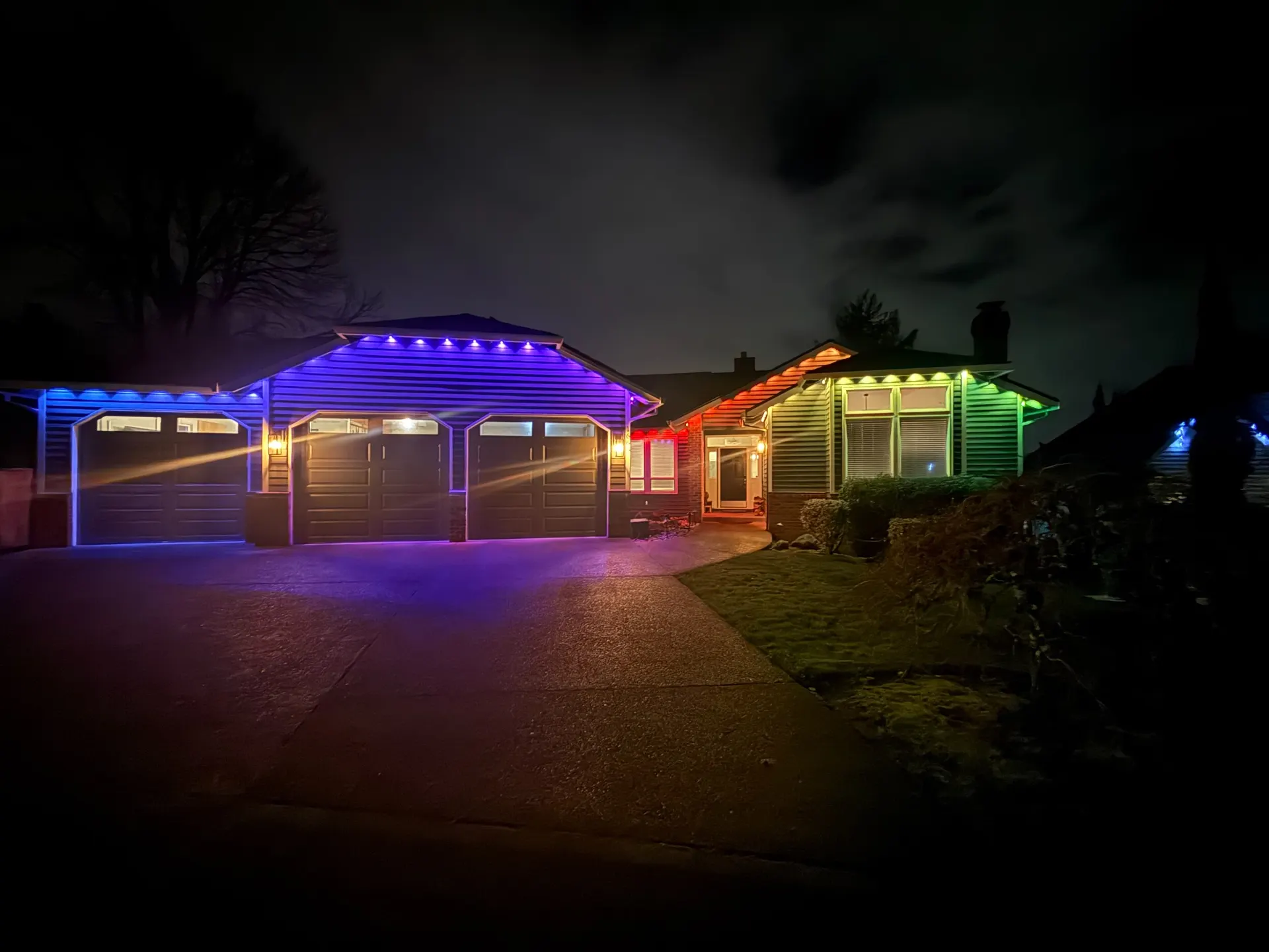 Permanent architectural LED lighting tracing the full roofline of a single-story home in a smooth blue-to-green gradient at night