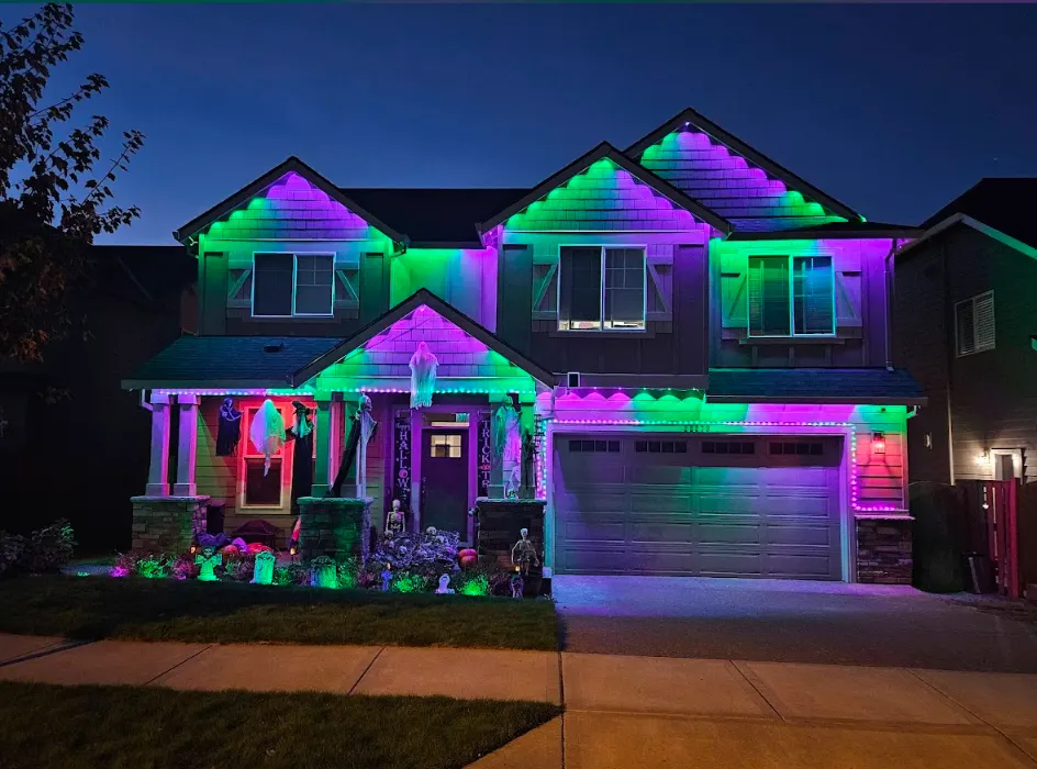 Permanent architectural LEDs programmed to green and purple for Halloween across a two-story home's rooflines and porch
